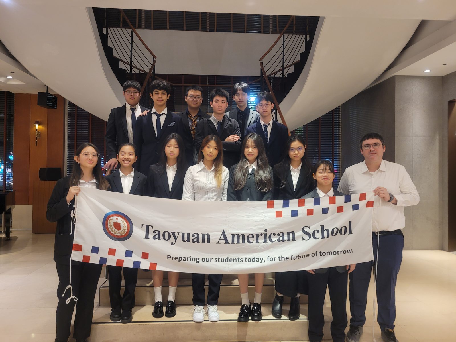 The TYAS delegation and their advisor holding the Taoyuan American School banner at HSINMUN XXII